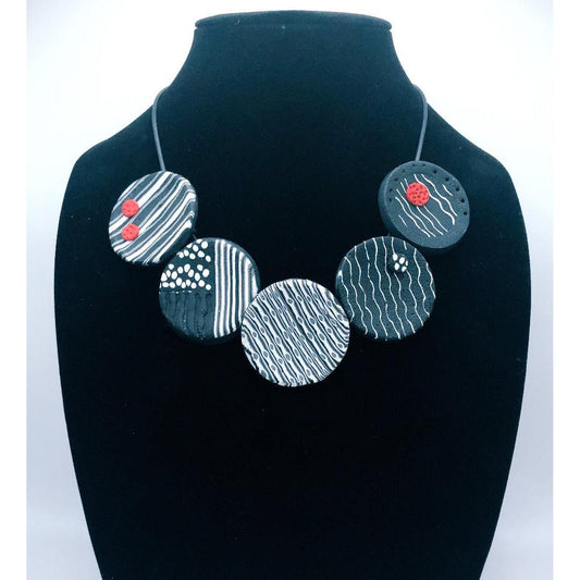 black & white, circles necklace with a red dot accent.